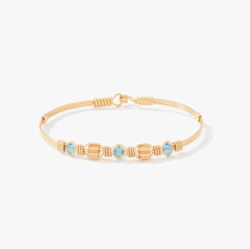 Gold bracelet with blue gemstones on a white background