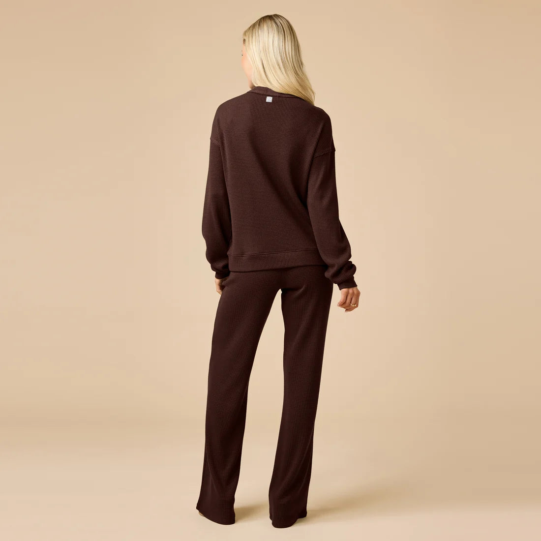 Person wearing a brown tracksuit on a beige background