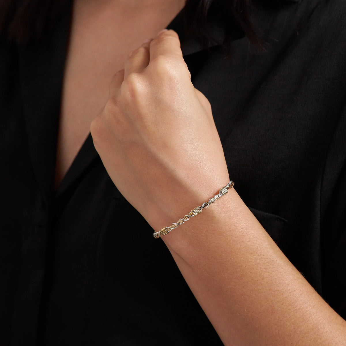 Person wearing a gold bracelet on a black background