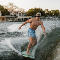 Man wakeboarding on a lake with houses and trees in the background