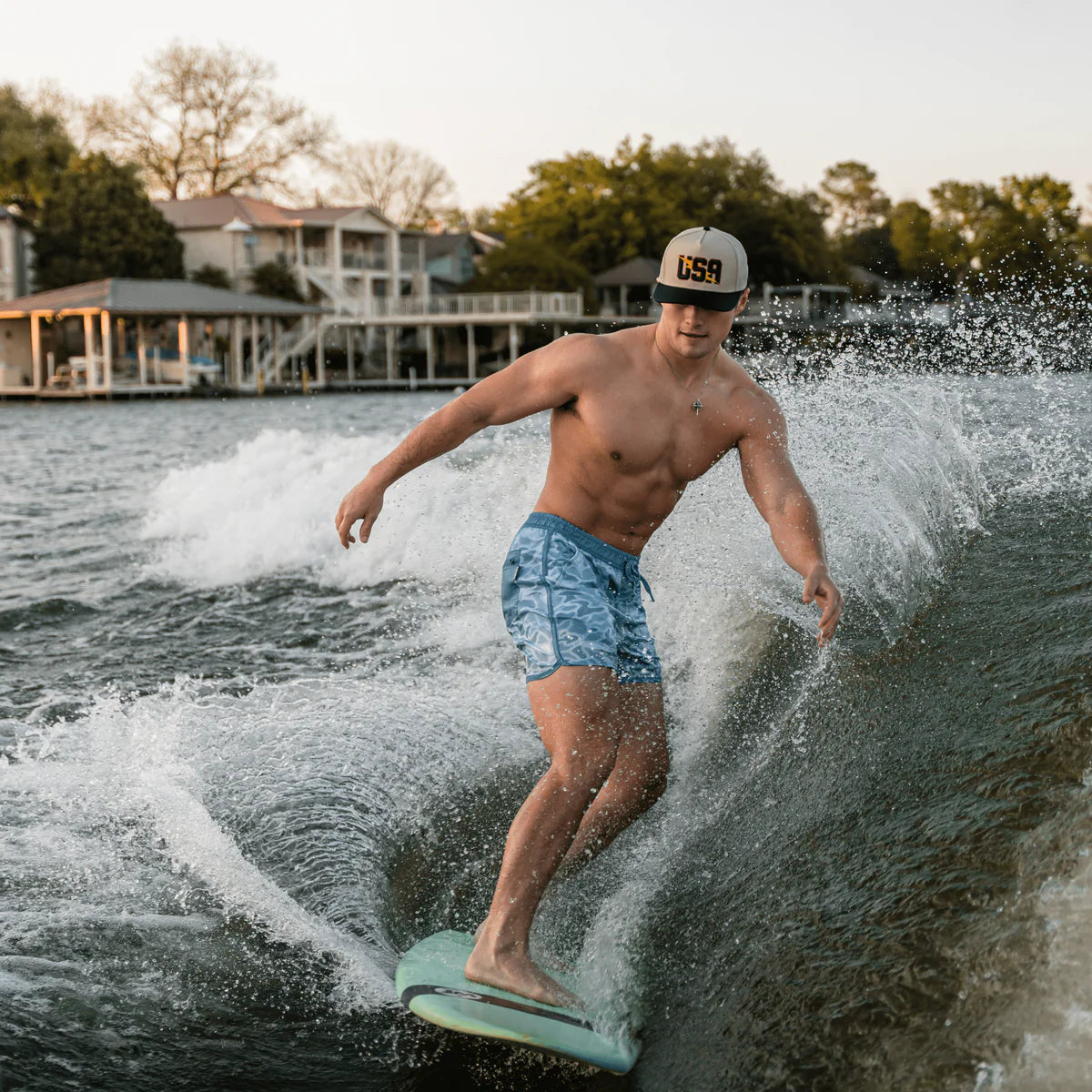 Man wakeboarding on a lake with houses and trees in the background