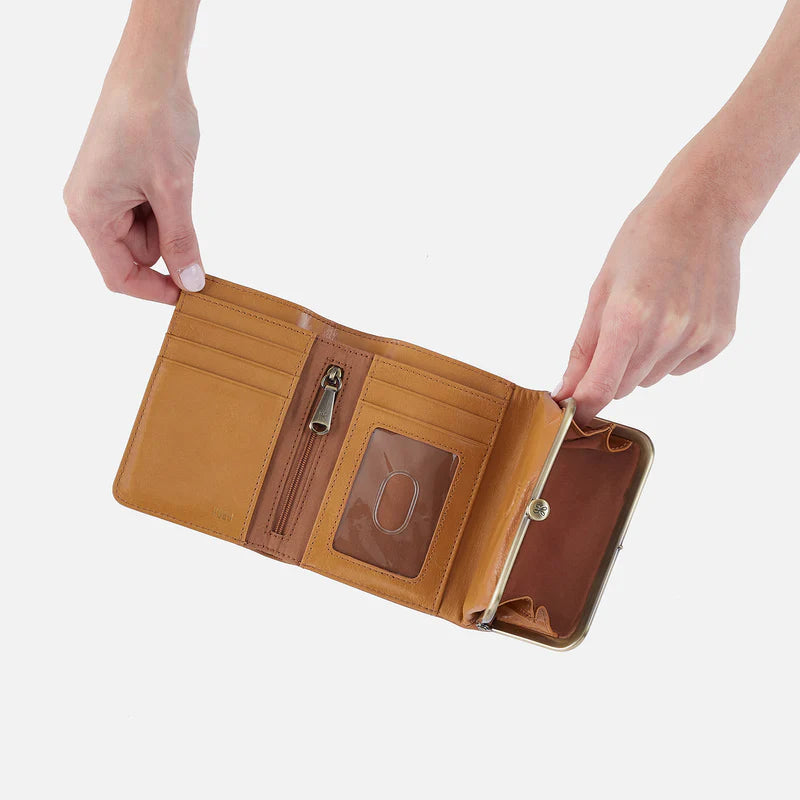 Brown leather wallet with a zipper pocket held open by hands on a white background