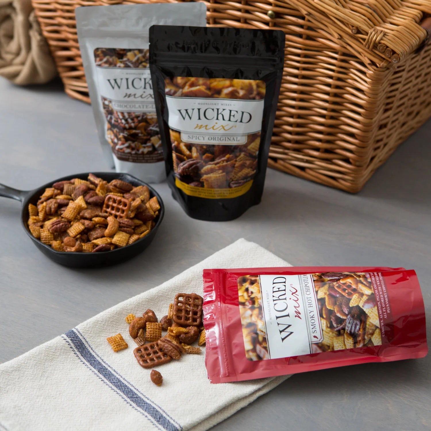 Wicked Snax snack packages on a table with a wicker basket in the background.