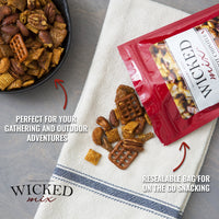 Wicked mix snack bag with open bag and snacks on a towel, bowl of mix in the background.