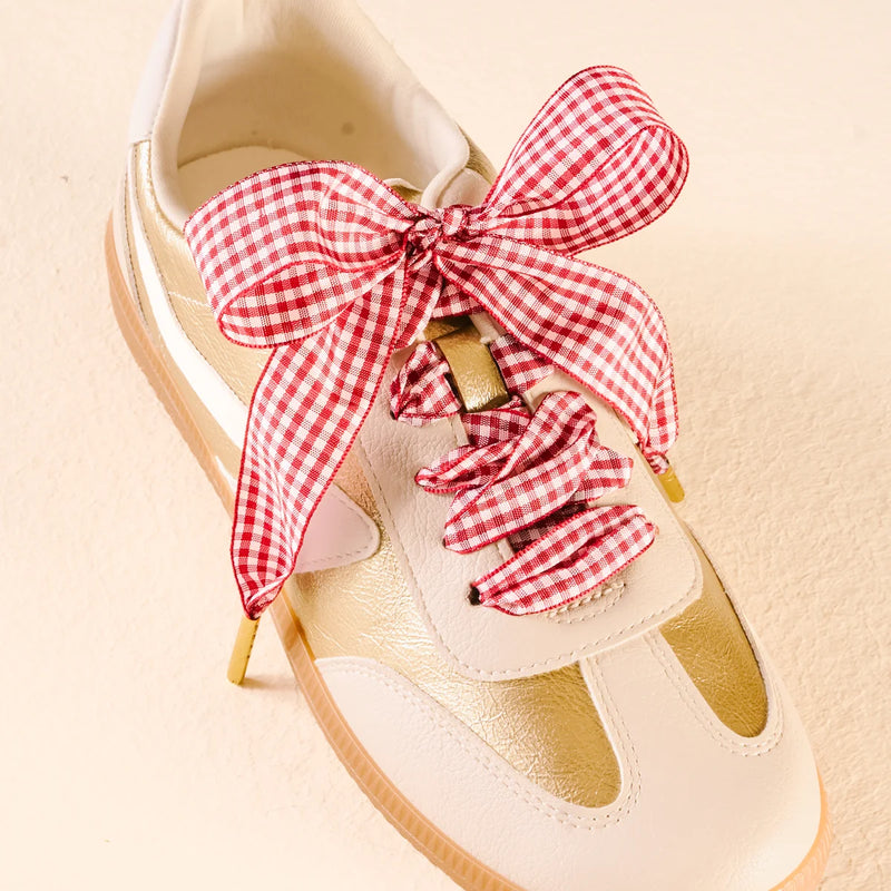 Beige sneaker with a red and white checkered bow and matching scrunchie on a beige background