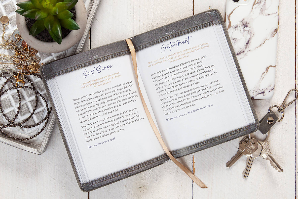 Open notebook with pages open on a marble surface with keys and a plant.