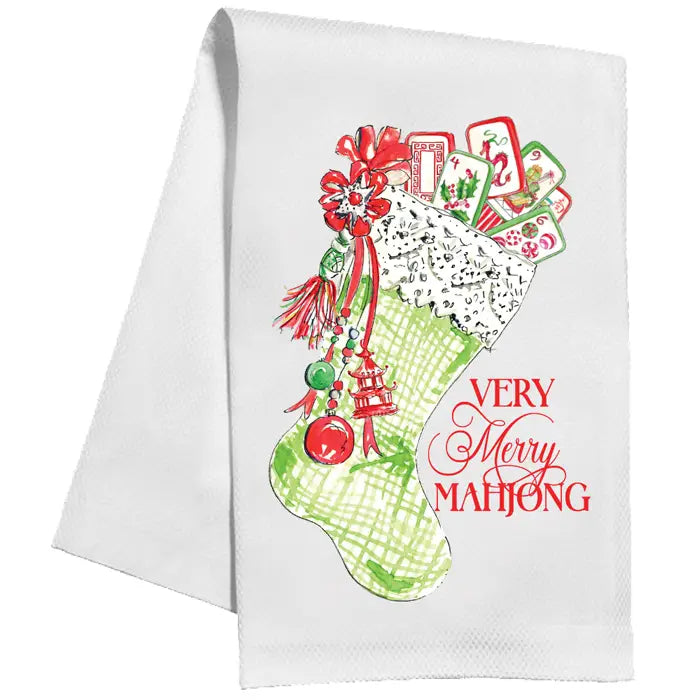 A white kitchen towel featuring a festive Christmas stocking graphic filled with playing cards and ornaments, alongside the red text 'VERY Merry MAHJONG'.