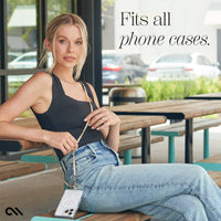 Woman sitting outdoors holding a phone case with text 'Fits all phone cases'.