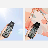 Digital light meter held by a hand with a clear blue sky background