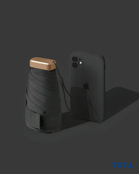 Black umbrella with gold handle next to a black smartphone on a dark background