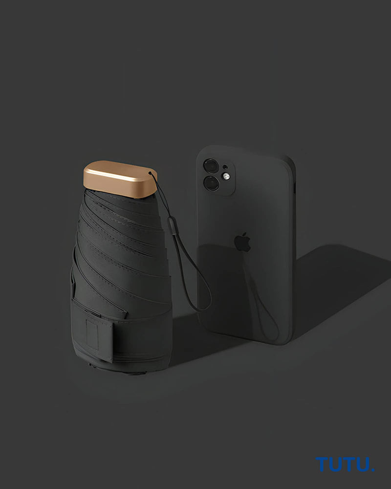 Black umbrella with gold handle next to a black smartphone on a dark background