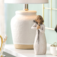 Decorative angel figurine on a shelf with a lamp and small plant in the background
