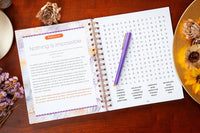 Open book with a puzzle and pen on a wooden surface with decorative elements