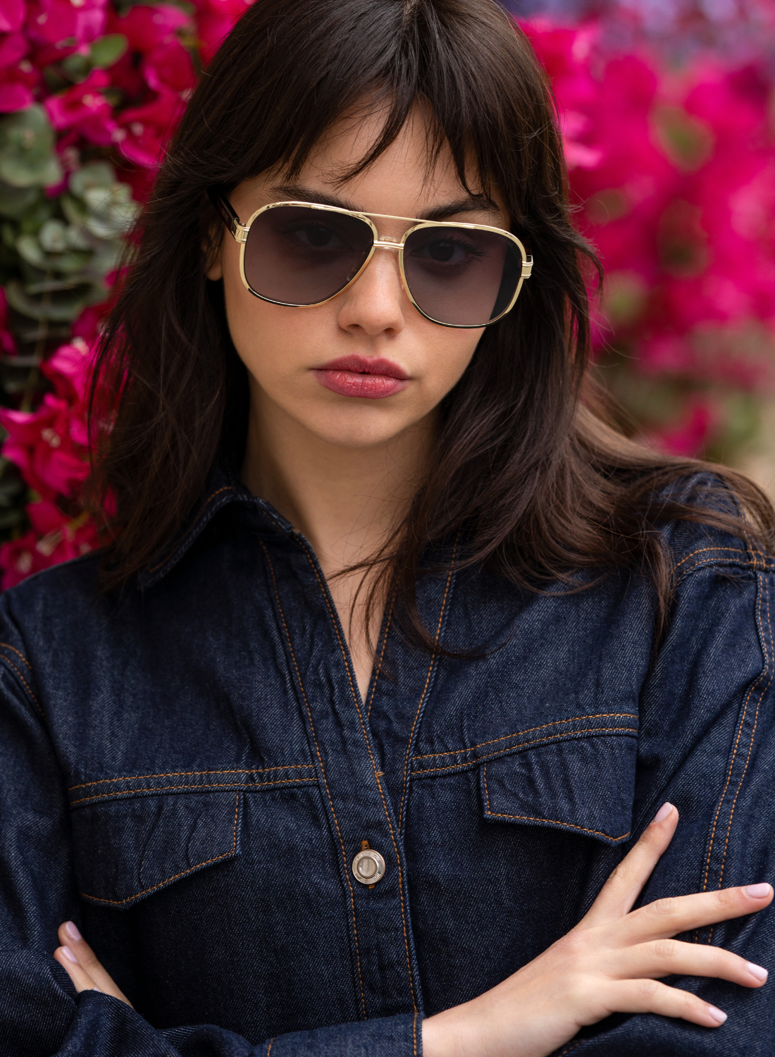 Woman wearing sunglasses and a denim jacket with a floral background