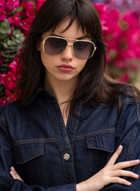 Woman wearing sunglasses and a denim jacket with a floral background