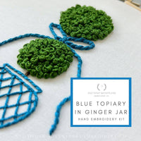 Embroidery kit with green and blue topiary design on a white background, featuring the brand 'And Other Adventures'.