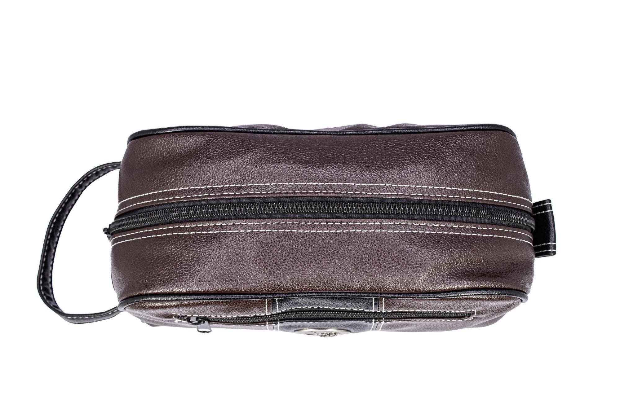 Brown leather toiletry bag with zippers on a white background