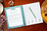 Open notebook with a word search puzzle on a wooden surface with decorative elements.