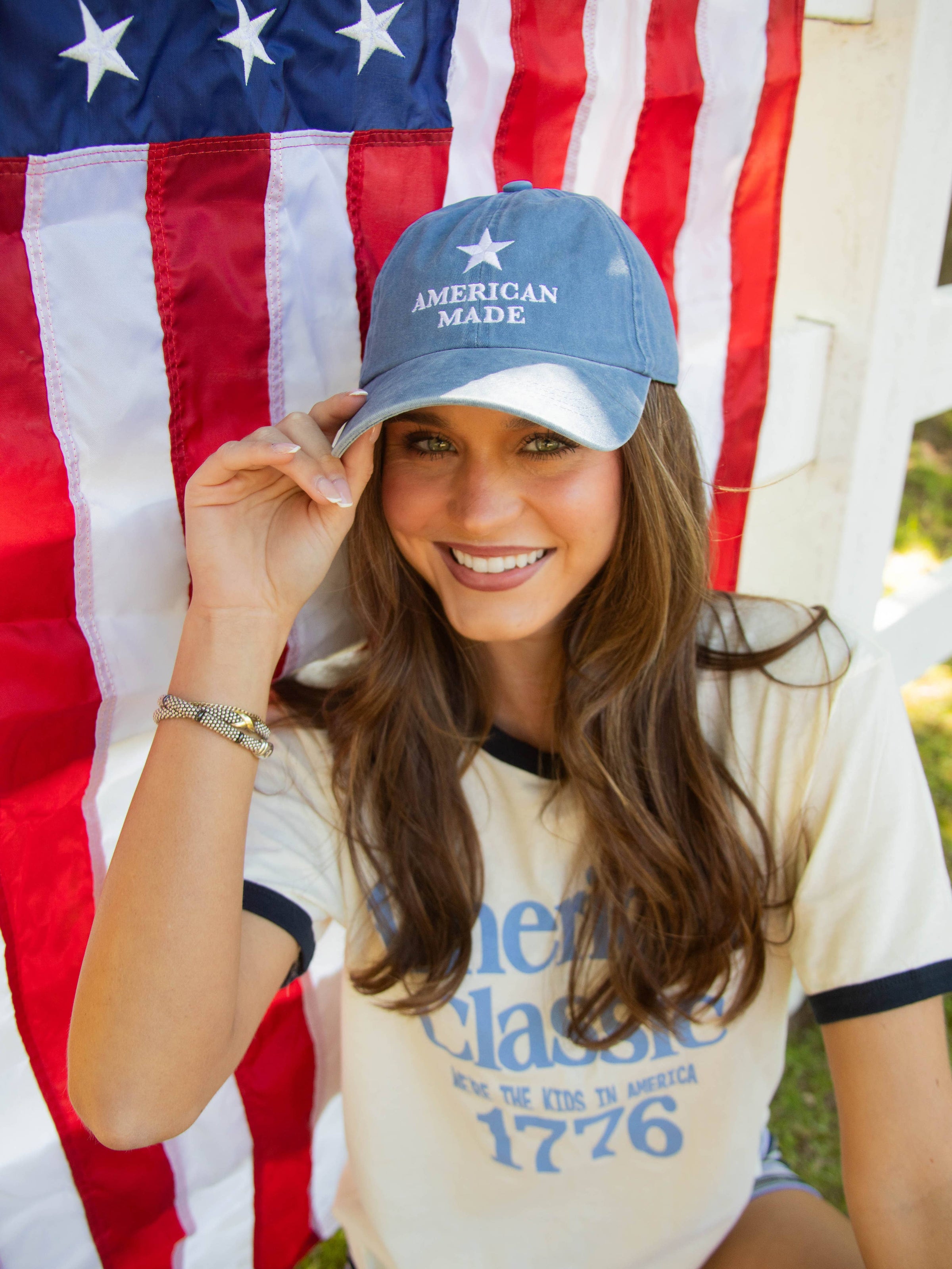 Woman wearing an 'American Made' cap in front of an American flag