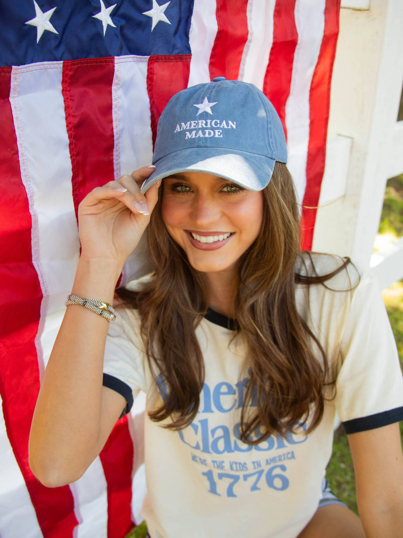Woman wearing an 'American Made' cap in front of an American flag