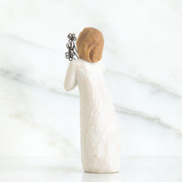 White ceramic figurine with textured surface and brown hair accessory on a marble background