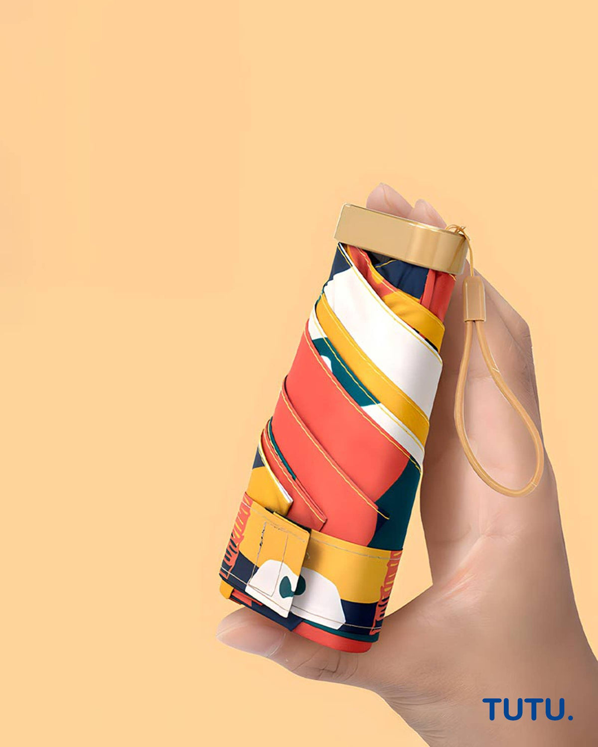 Colorful umbrella with geometric pattern held by a hand on a beige background, featuring the brand 'TUTU'.