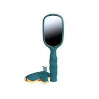 A teal handheld vanity mirror with a twisted handle, shown with a matching teal and gold stand and small accessory piece on a plain white background.