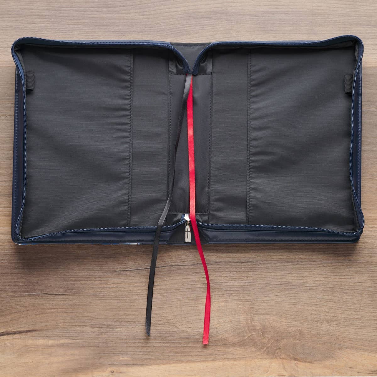 Black zippered pouch with a red drawstring on a wooden surface