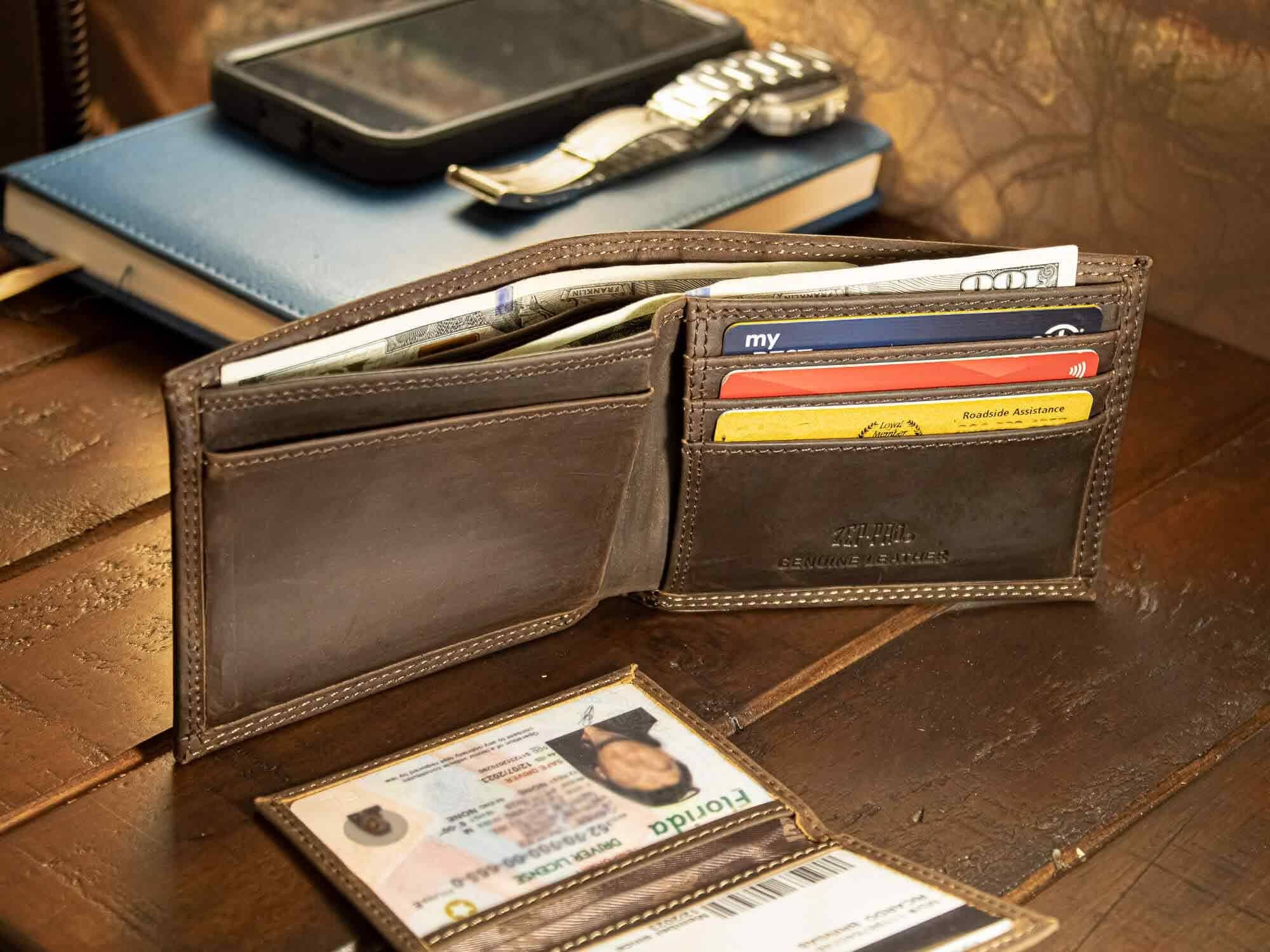 Brown leather wallet with various cards and an ID on a wooden surface.