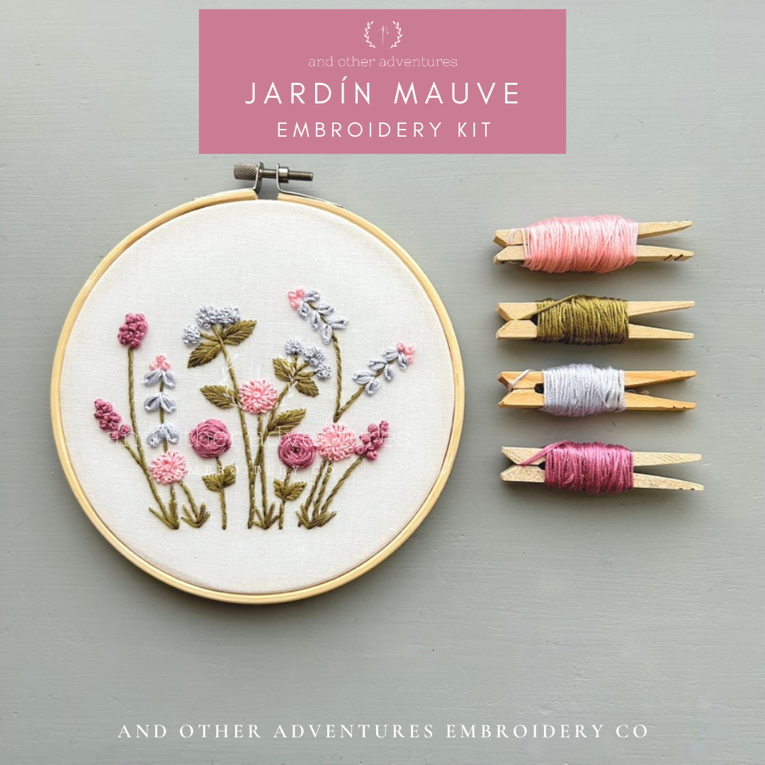 Embroidery kit with floral design, threads, and branding on a gray background