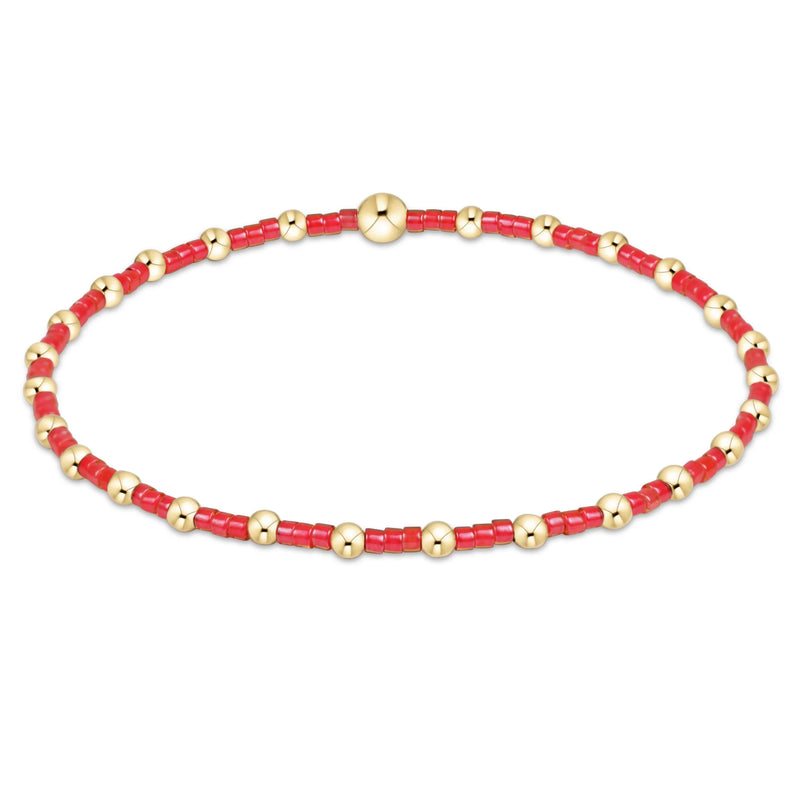 Bracelet with red beads and gold accents on a white background