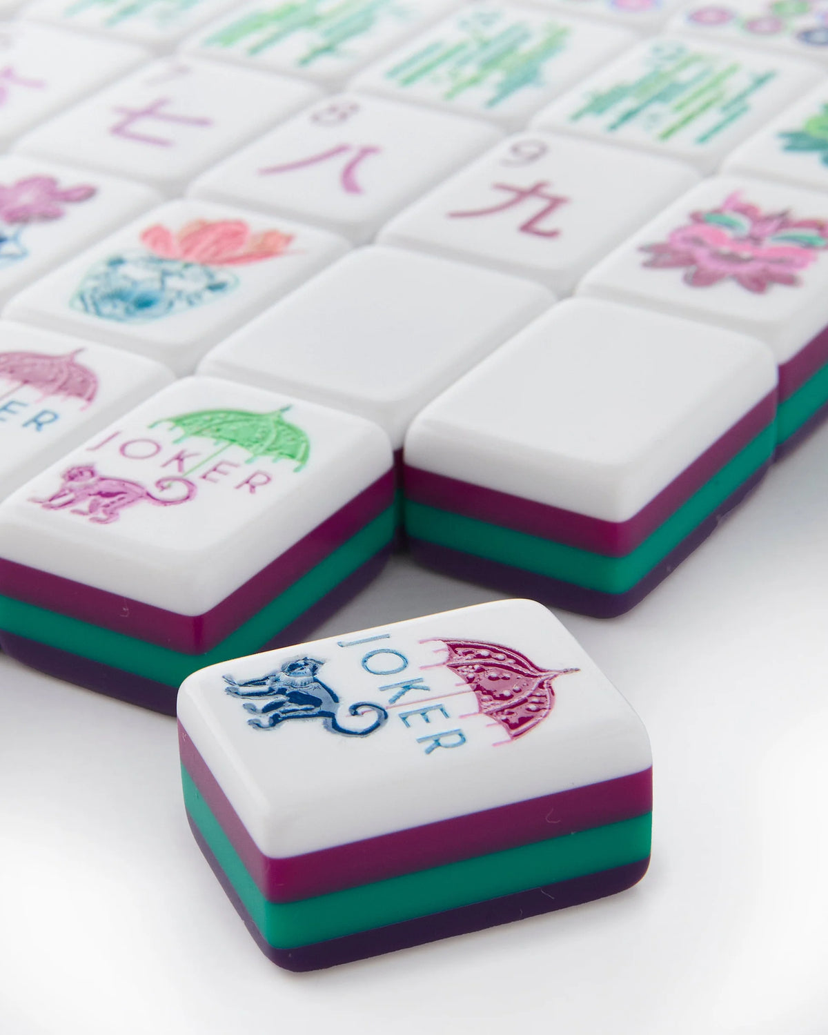 Close-up of colorful Mahjong tiles with various symbols on a white background