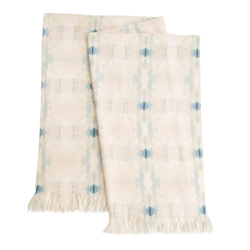 A folded cream-colored woven throw blanket with a light blue ikat pattern and fringed edges, displayed on a clean white background.