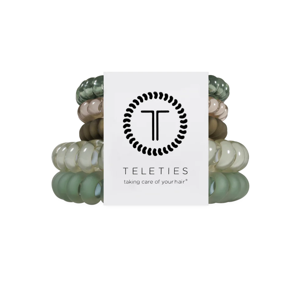 A set of six Teleties hair elastic bands in various shades of sage green, beige, and brown, bundled together with a white paper label featuring the black Teleties logo and brand name.