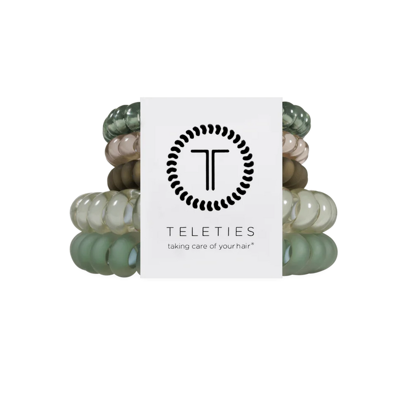 A set of six Teleties hair elastic bands in various shades of sage green, beige, and brown, bundled together with a white paper label featuring the black Teleties logo and brand name.