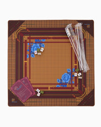 A top-down view of the Mahjong Mat on a clean white background. The square board features a brown and gold houndstooth pattern with a central tan grid, decorated with blue floral motifs in the corners.