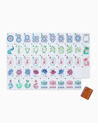 A set of Mahjong tiles arranged in a grid on a white background, with a small wooden box at the bottom right. The tiles feature traditional Chinese symbols and characters in blue, pink, green, and red on a white base.