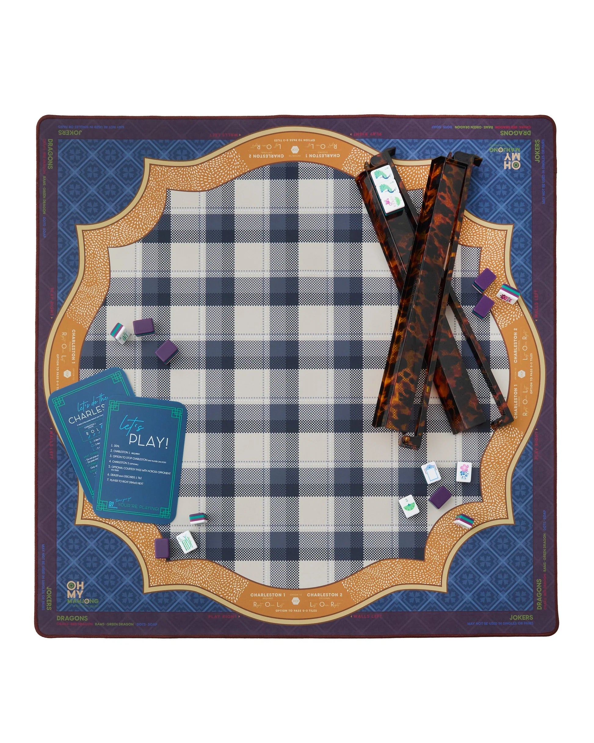 Mahjong setup on a checkered mat with cards and pieces.